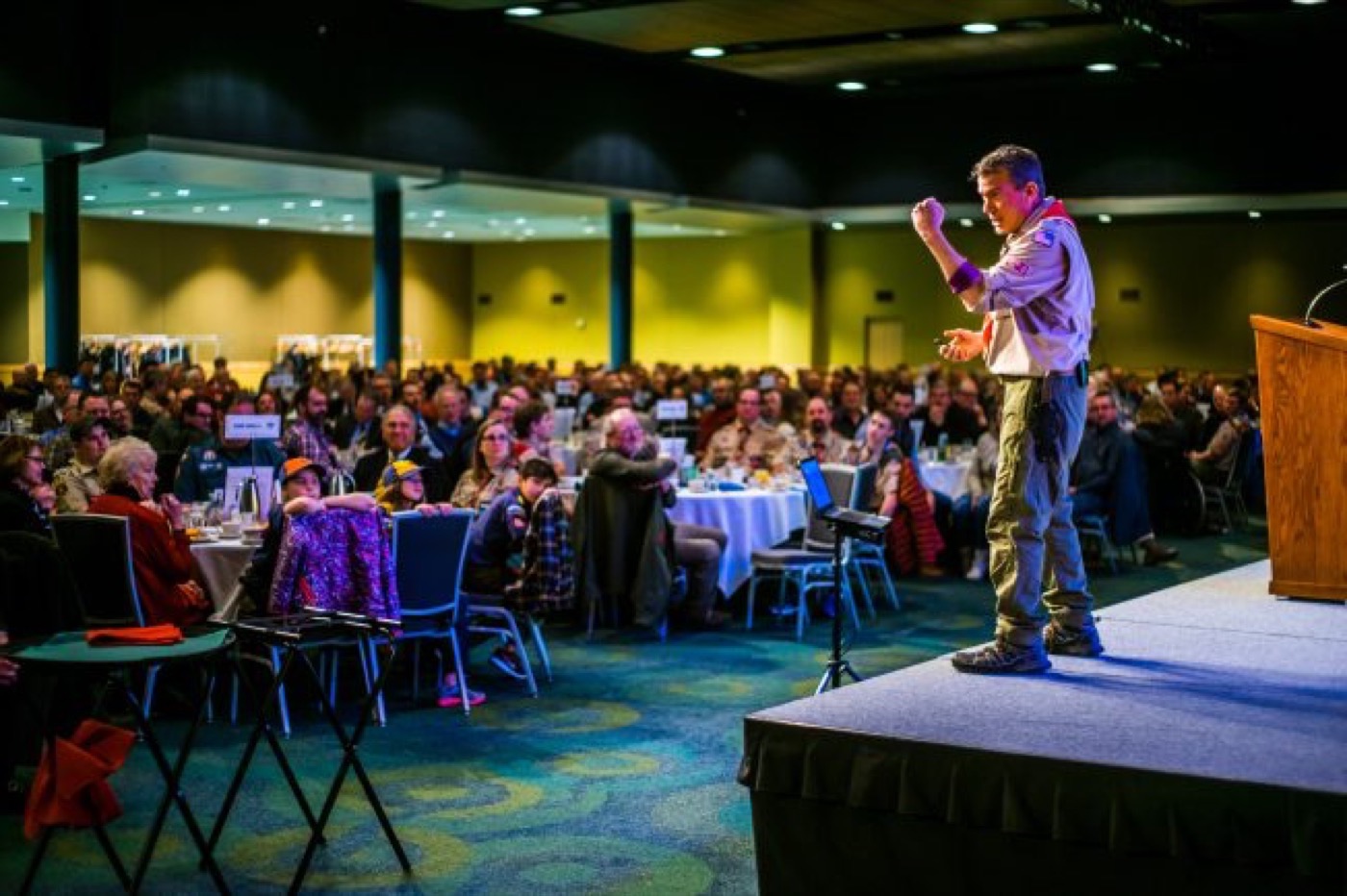 Terry L. Fossum in his Scoutmaster uniform on stage before a packed Scouting fundraising event